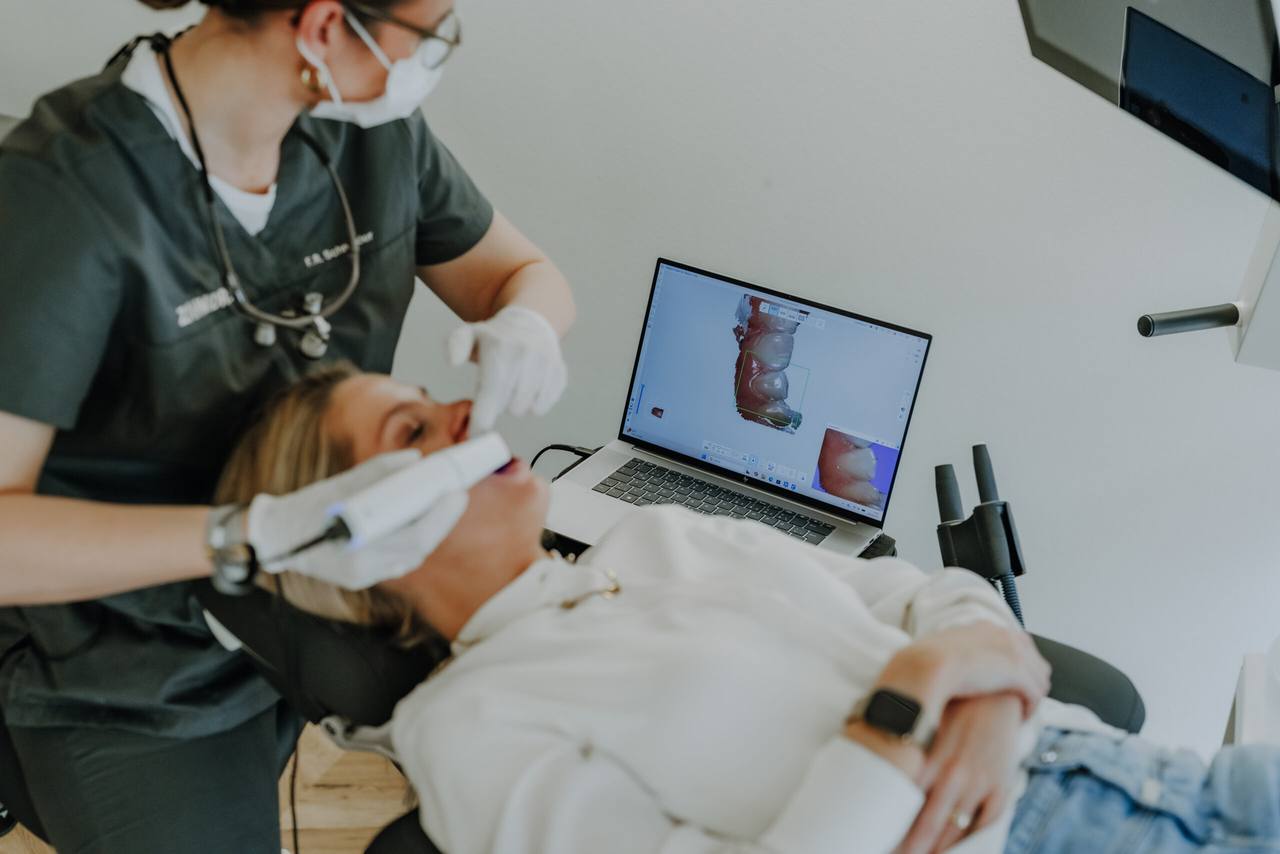 Intraoralscanner im Einsatz, auf dem Laptop entsteht live das digitale 3D-Modell der Zähne