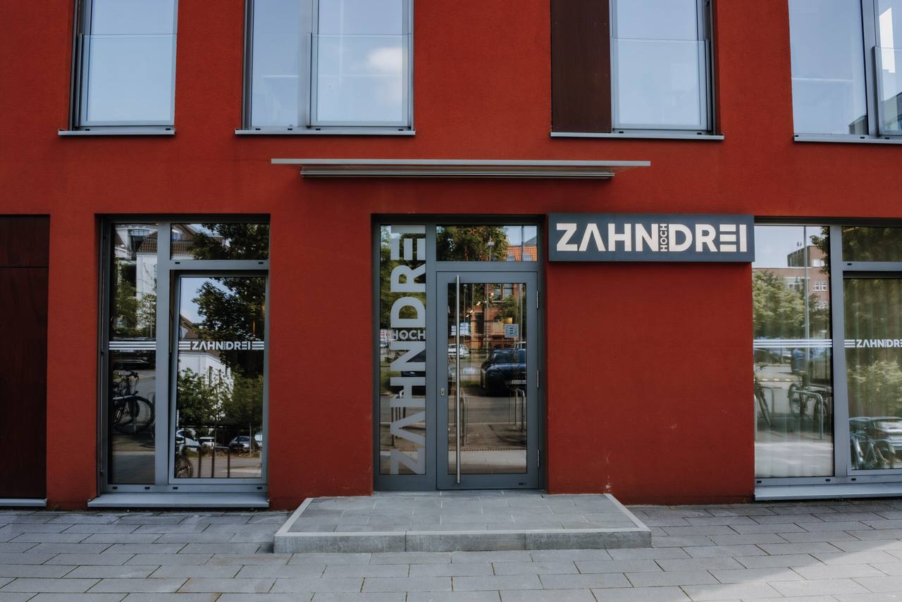 Eingang der Praxis zahnhochdrei mit Schriftzug an roter Fassade auf dem Hanomaggelände