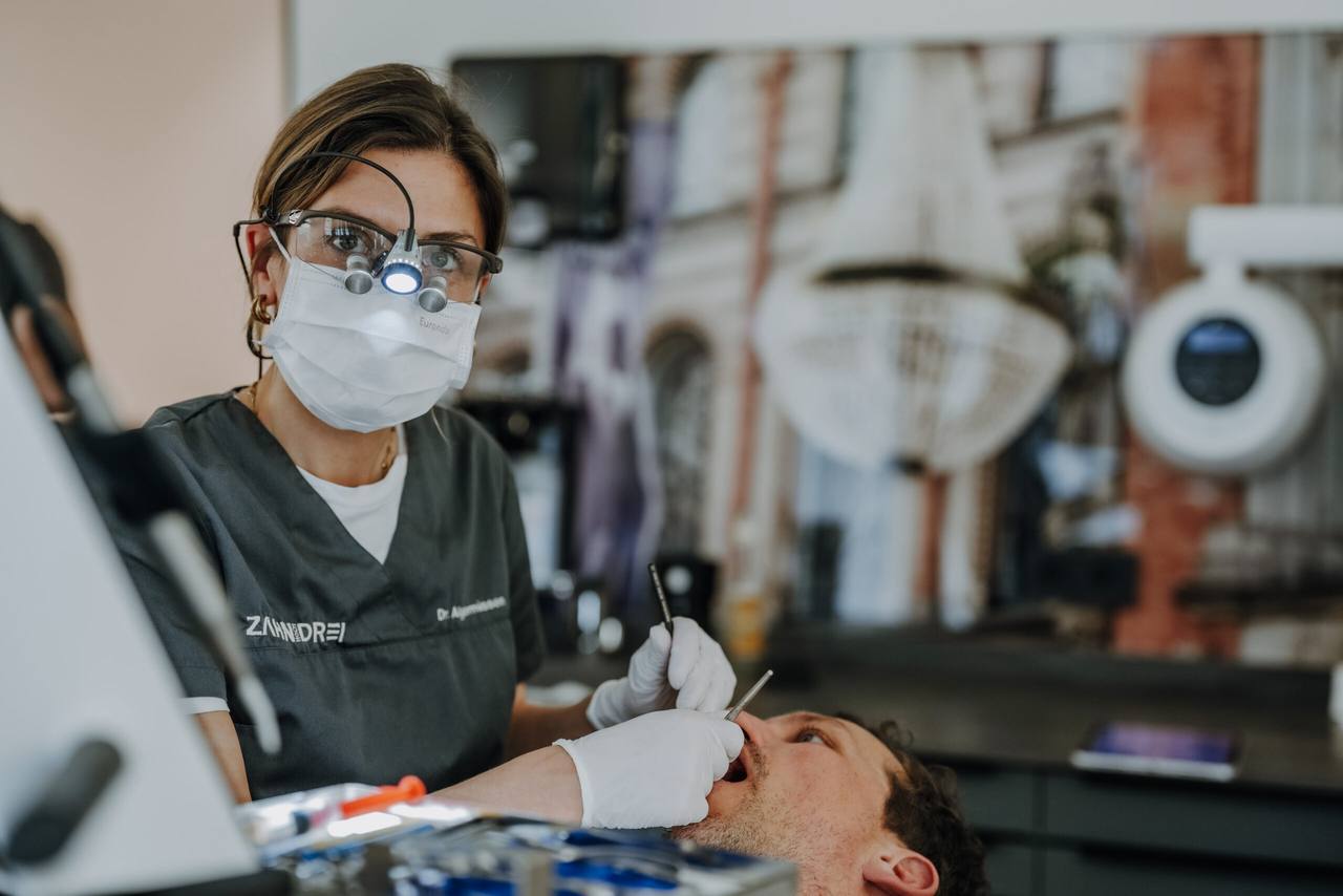 Dr. Teresa Algermissen mit Lupenbrille und Stirnlicht bei einer Behandlung am Patienten