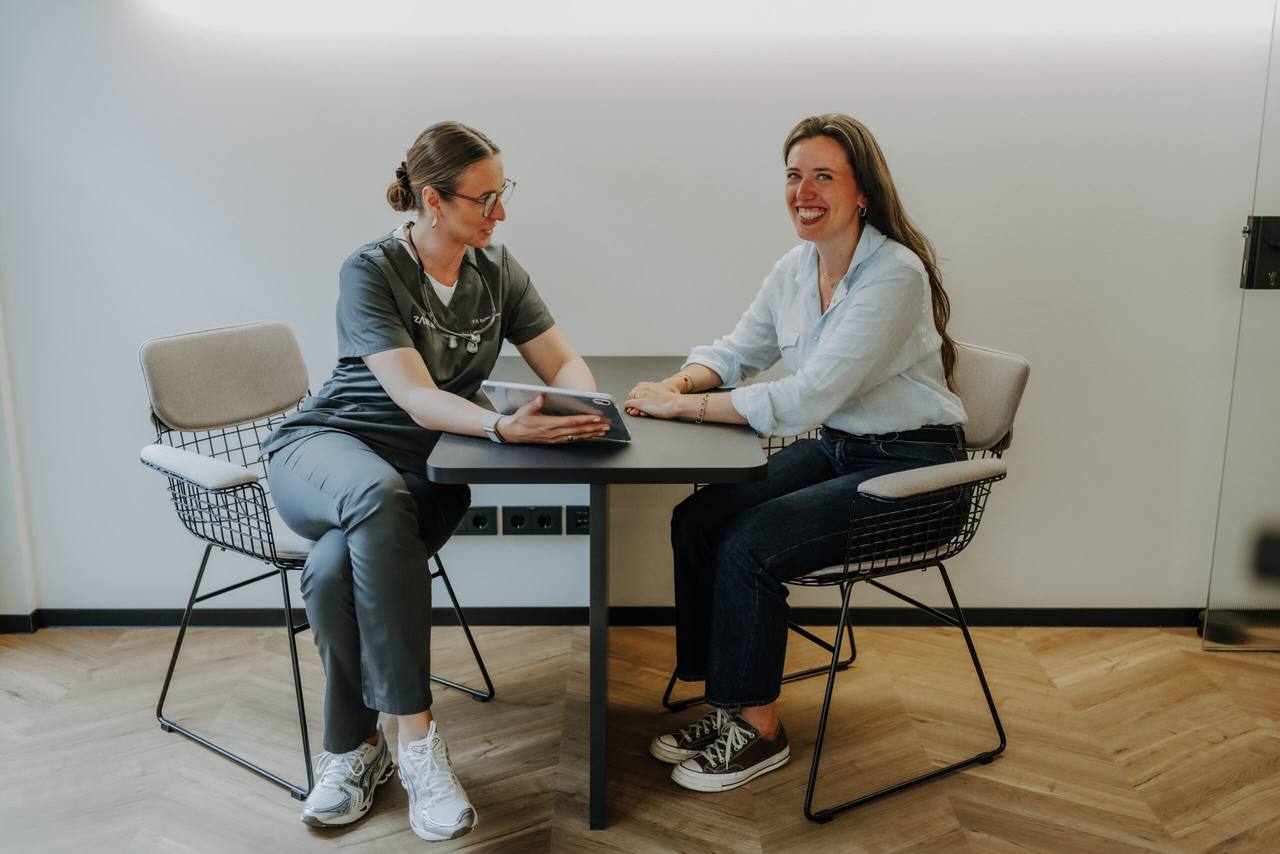 Franziska-Roberta Schneider berät eine strahlende Patientin am Tisch